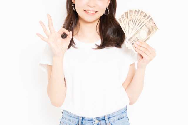 OKサインをするお金を持つ女性