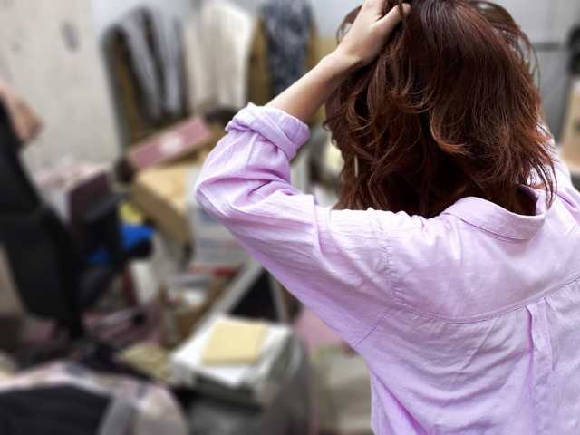 不用品で散らかった部屋と頭を抱える女性